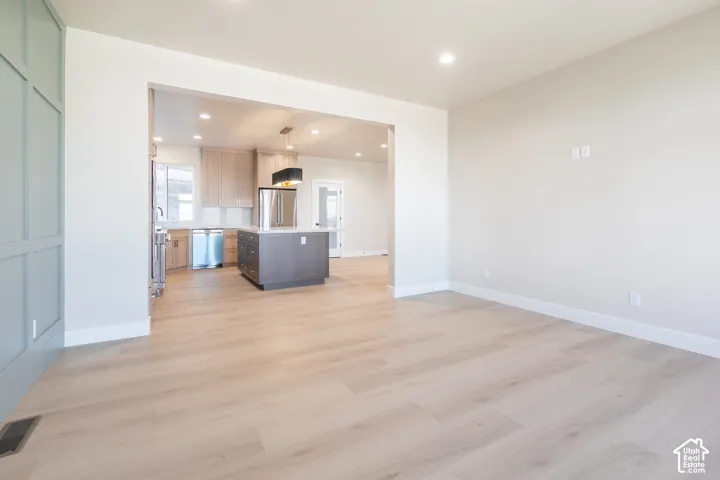 Open concept layout with wood-finish flooring, recessed lighting, and a kitchen featuring stainless steel appliances and an island