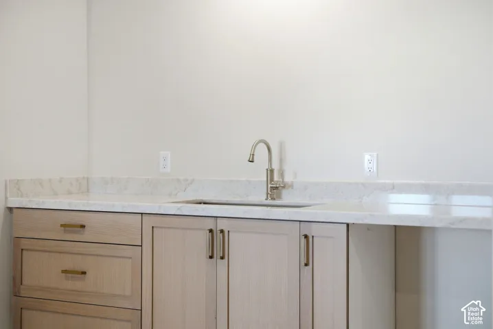 Light-toned cabinetry with gold-toned hardware, undermount sink, gooseneck faucet, and light-toned stone countertop