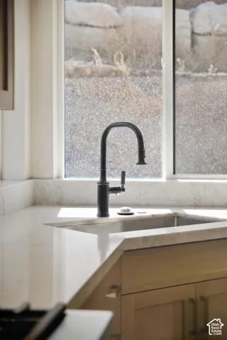 Undermount sink with a matte black gooseneck faucet, light-toned countertop, and light wood-finish cabinetry