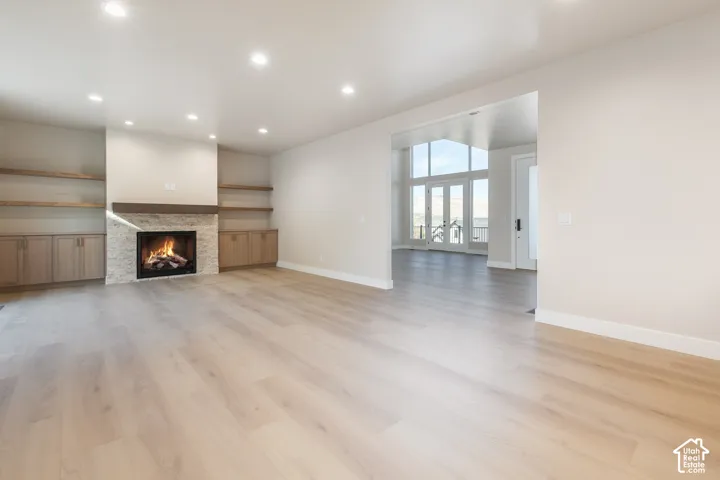 Spacious living area featuring wood-finish flooring, recessed lighting, and a fireplace with stone surround