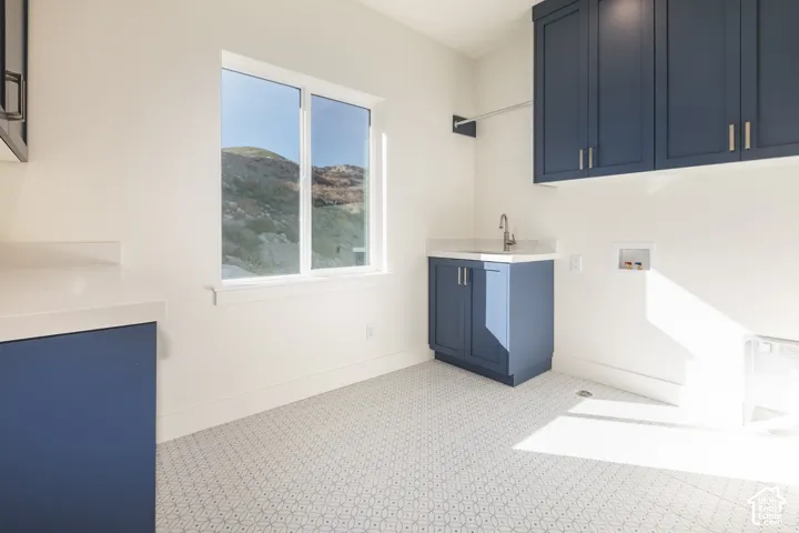 Built-in cabinetry in a deep blue finish, light-colored countertops, white walls, patterned tile flooring, and a window with a mountain backdrop