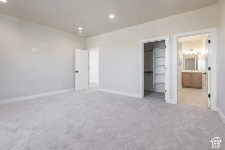Spacious room featuring light-colored carpeting, recessed lighting, and a built-in closet with shelving
