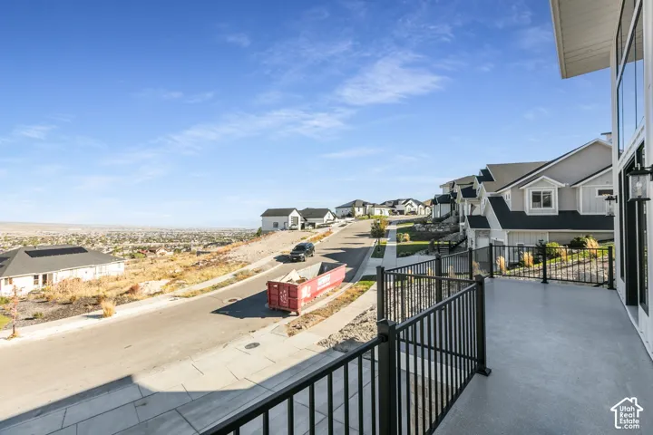 Expansive outdoor deck with dark metal railings and integrated wall sconces, featuring a distant cityscape