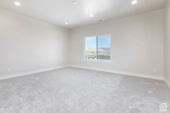 Recessed ceiling lighting, light gray wall paint, window with mountain backdrop, light gray carpeting, and white trim