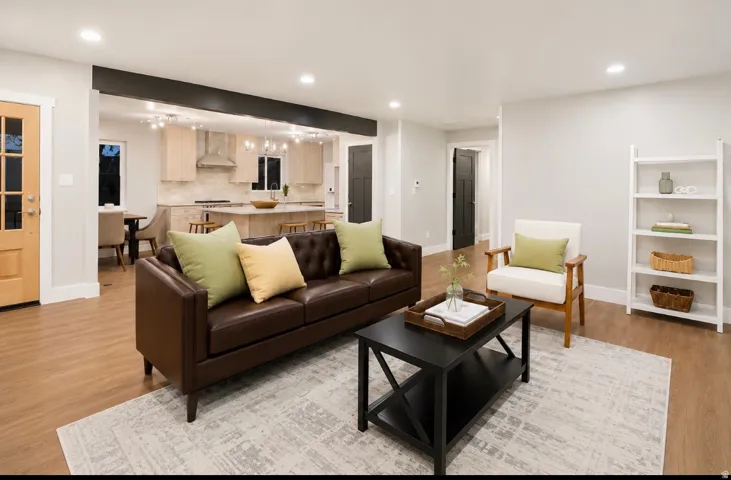 Open-concept living space featuring wood-finish flooring, recessed lighting, a light wood-finish entry door with glass panes, and a kitchen visible with light wood-finish cabinetry