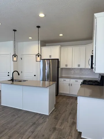 Modern kitchen featuring white shaker cabinetry, stainless steel appliances, and wood-finish flooring