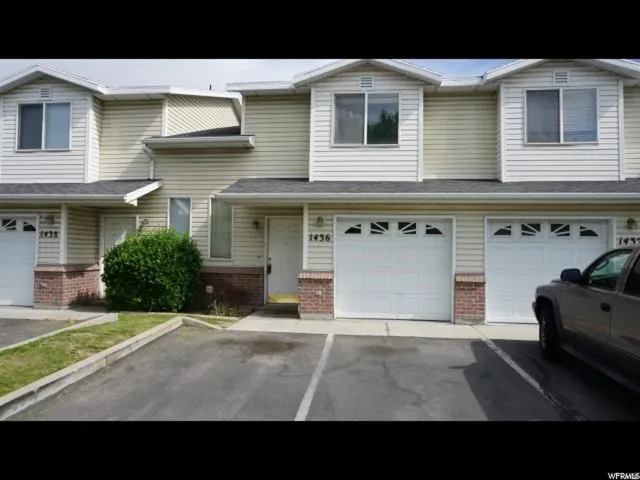 Townhome exterior featuring light-colored siding and brick accents