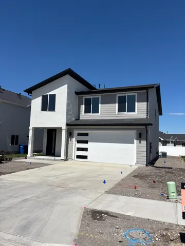 Two-story residence featuring a combination of stucco and horizontal siding, a two-car garage with modern frosted glass panels, an extended concrete driveway, and an inviting covered porch entry