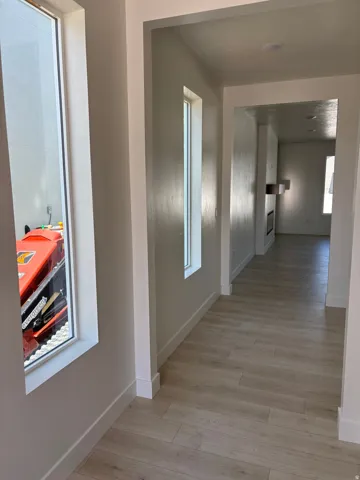 Light wood-finish flooring, recessed lighting, and bright white window trim