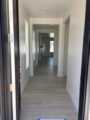 Recessed lighting, light wood-finish flooring, white painted walls, and an open entryway