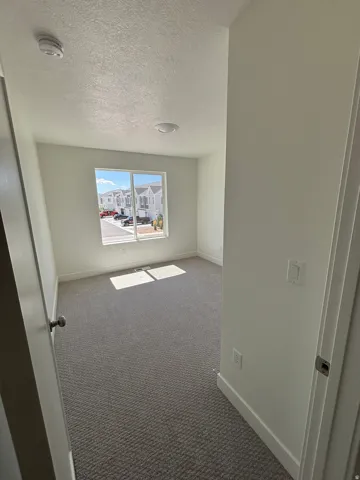Neutral wall color, textured carpeting, recessed lighting, and a single window