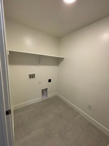 Utility area featuring light-toned walls, tile flooring, and an overhead light fixture