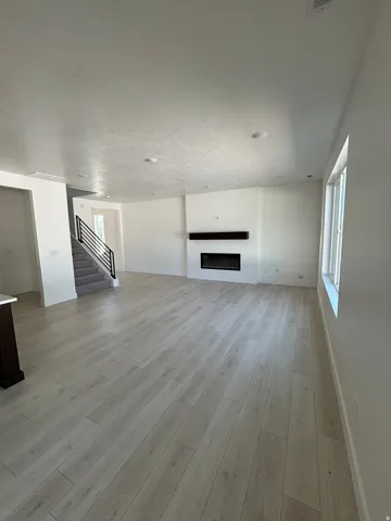 Bright living space featuring wood-finish flooring, a built-in electric fireplace with a dark wood mantel, and recessed ceiling lighting