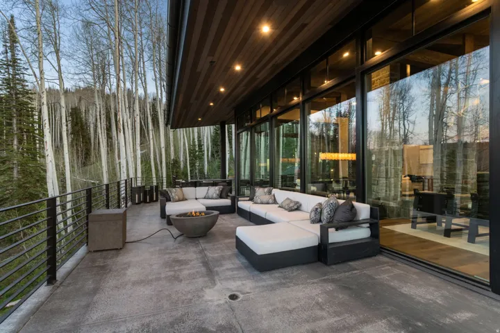 Expansive concrete patio with a built-in fire pit, surrounded by black metal railings