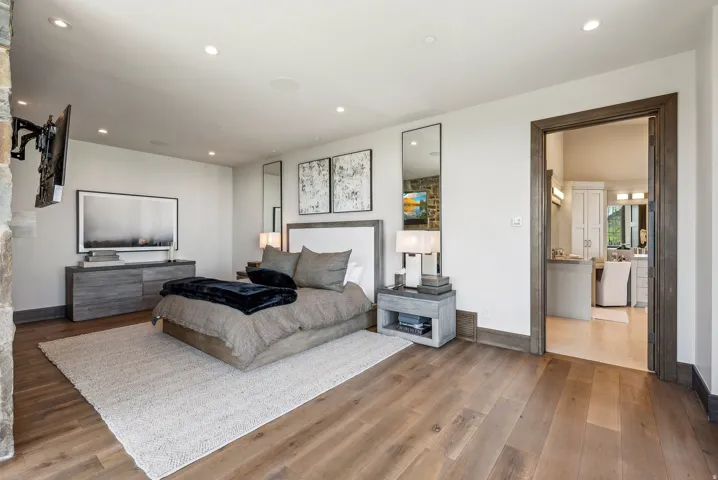 Spacious room featuring wide plank wood-finish flooring, recessed lighting, and a stone accent wall