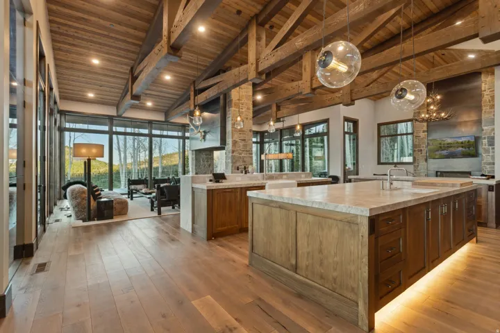 Open concept interior featuring wide plank wood-finish flooring and a vaulted wood-paneled ceiling with exposed beams