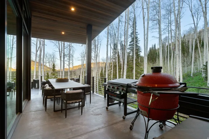 Expansive outdoor deck featuring a concrete floor, wood-paneled ceiling with recessed lighting, and a cable railing system