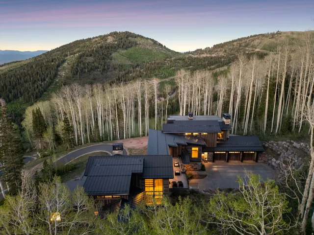 Contemporary mountain residence featuring multiple levels, extensive dark-toned metal roofing, and multiple garages with wood-paneled doors