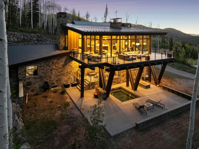 Modern mountain residence featuring a stone and wood exterior with a metal roof