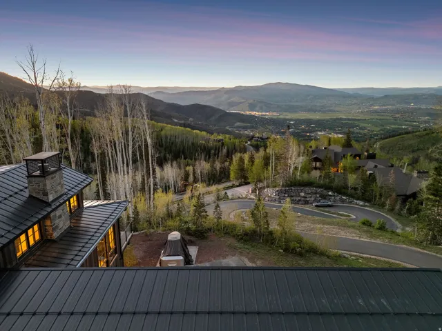 Expansive mountain landscape featuring a winding paved road and mature trees
