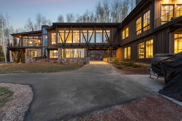 Modern architectural residence featuring extensive glazing, stone accents, wood siding, and multiple balconies
