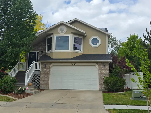Residential exterior featuring a two-car garage, bay windows, and a decorative octagonal window