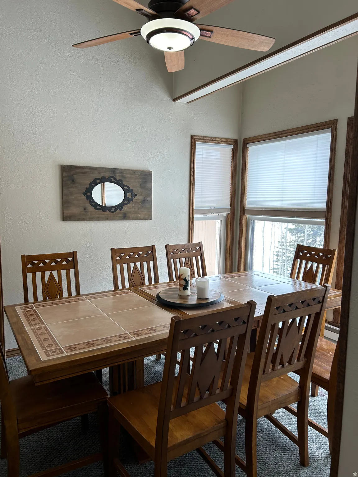 Dining area featuring vaulted ceilings, a ceiling fan with integrated lighting, and multiple windows with wood-finish trim