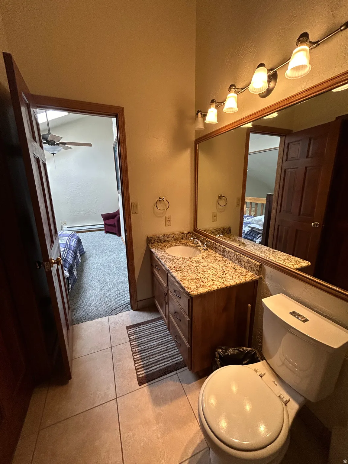 Bathroom vanity featuring a granite-style countertop, undermount sink, and wood-finish cabinetry
