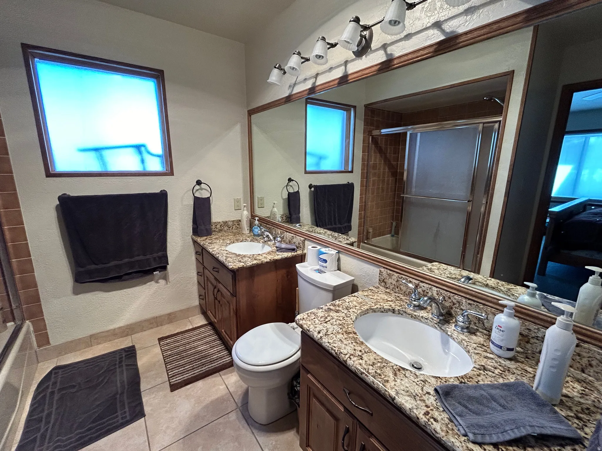 Dual wood-finish vanities with granite-style countertops and undermount sinks