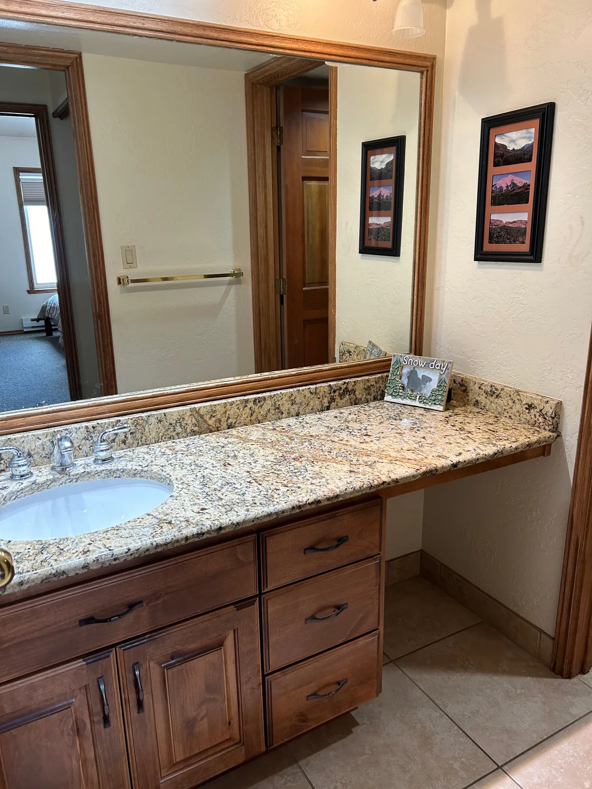 Bathroom vanity featuring a granite countertop, undermount sink, and wood-finish cabinetry with multiple drawers