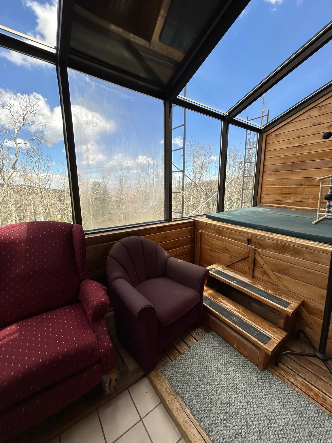 Sunroom featuring sloped glass walls and ceiling, natural wood paneling, and a raised platform with wooden steps