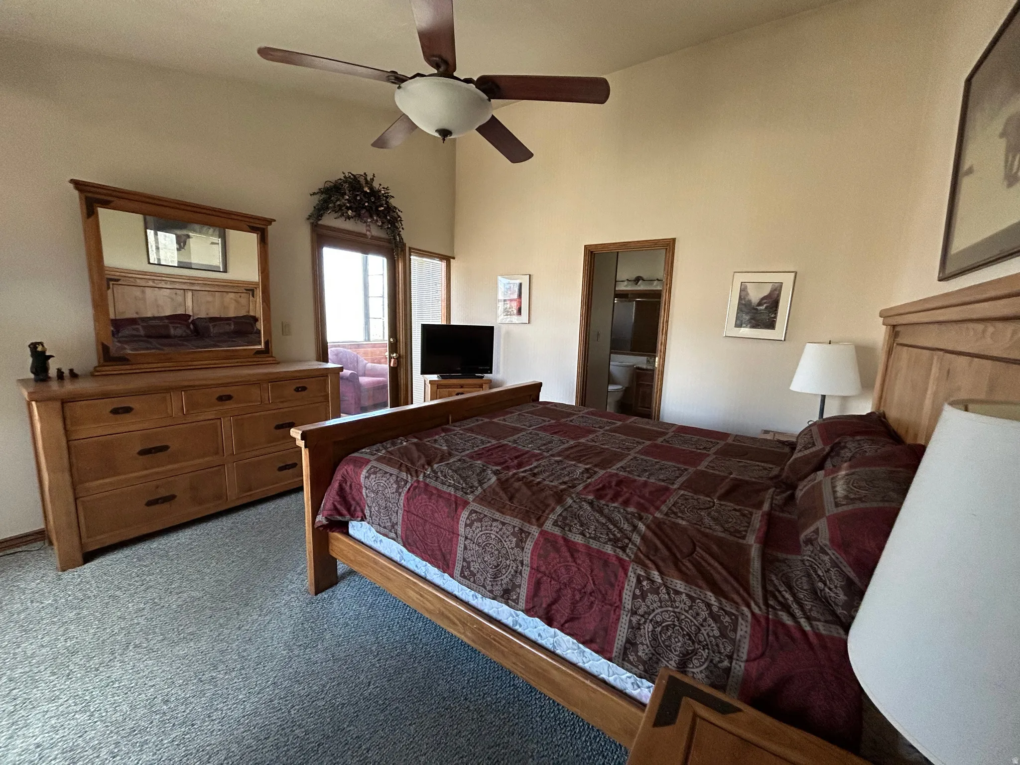 Spacious room featuring vaulted ceilings, light-toned wall finishes, and a ceiling fan with integrated lighting