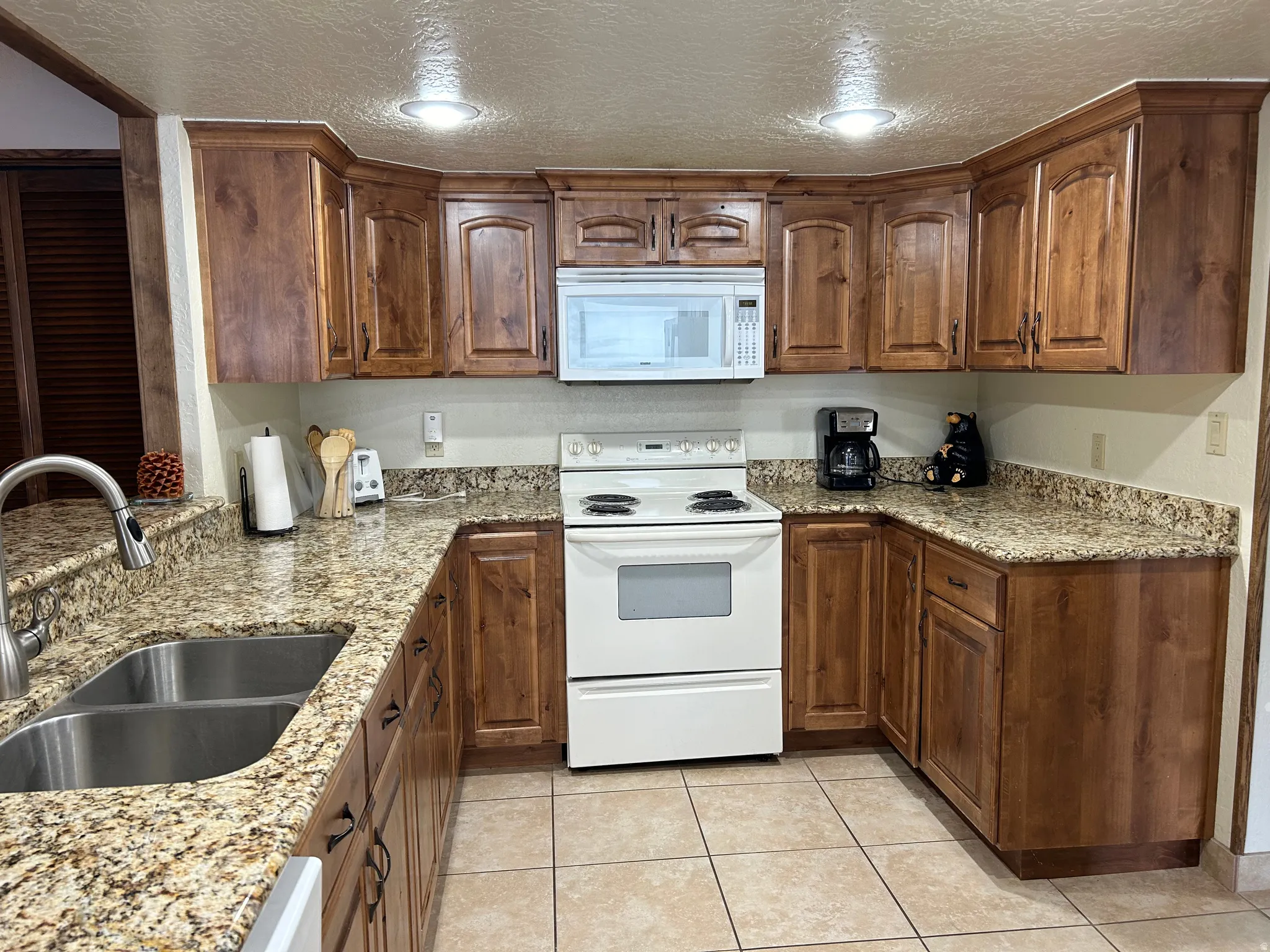 U-shaped kitchen featuring wood-finish cabinetry, light-toned speckled countertops, and tile flooring