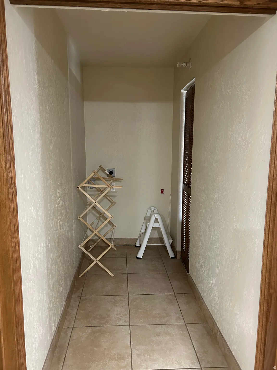 Dedicated utility space featuring tile flooring, neutral wall finish, and a wood-finish doorway