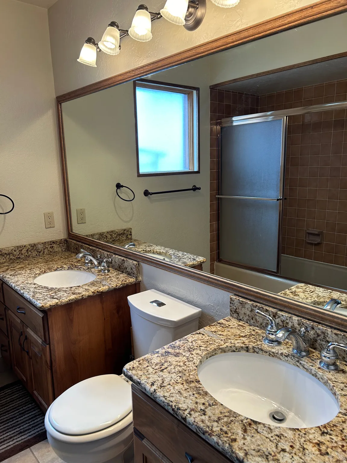 Dual vanity with granite countertops, undermount sinks, and wood cabinetry