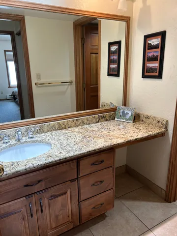 Bathroom vanity featuring a granite countertop, undermount sink, and wood-finish cabinetry with multiple drawers