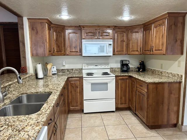 U-shaped kitchen featuring wood-finish cabinetry, light-toned speckled countertops, and tile flooring