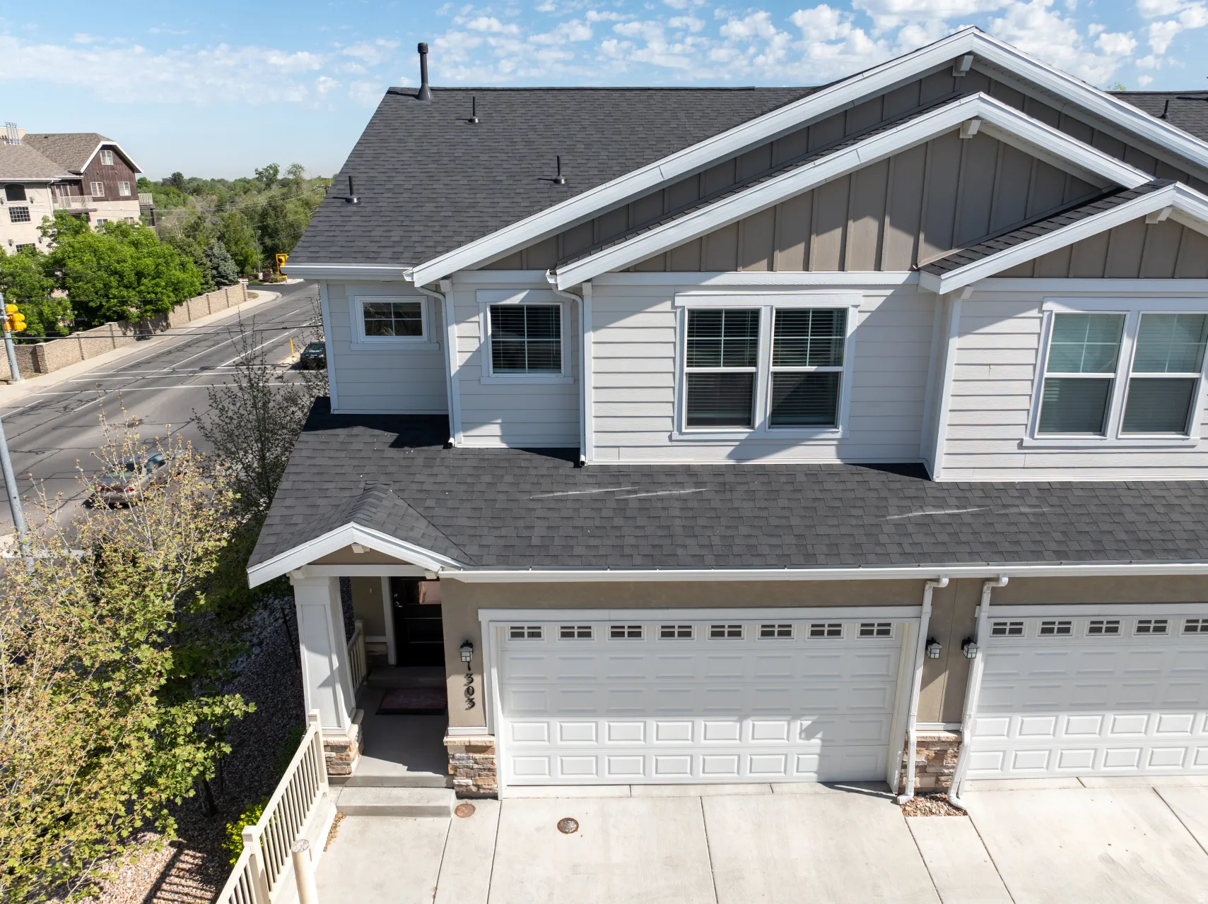 Contemporary multi-level residence featuring light-colored siding and a dark shingle roof
