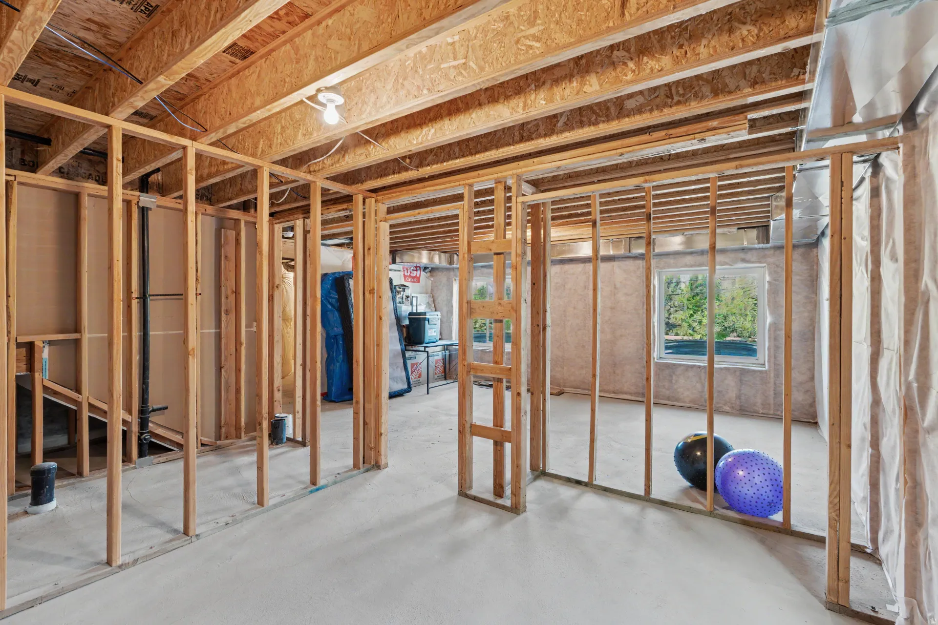 Unfinished lower level with exposed wood framing, concrete flooring, and visible ceiling joists