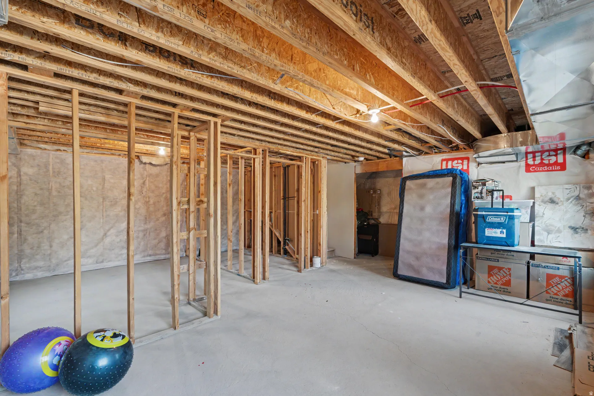 Unfinished basement space featuring exposed wood joists and concrete flooring