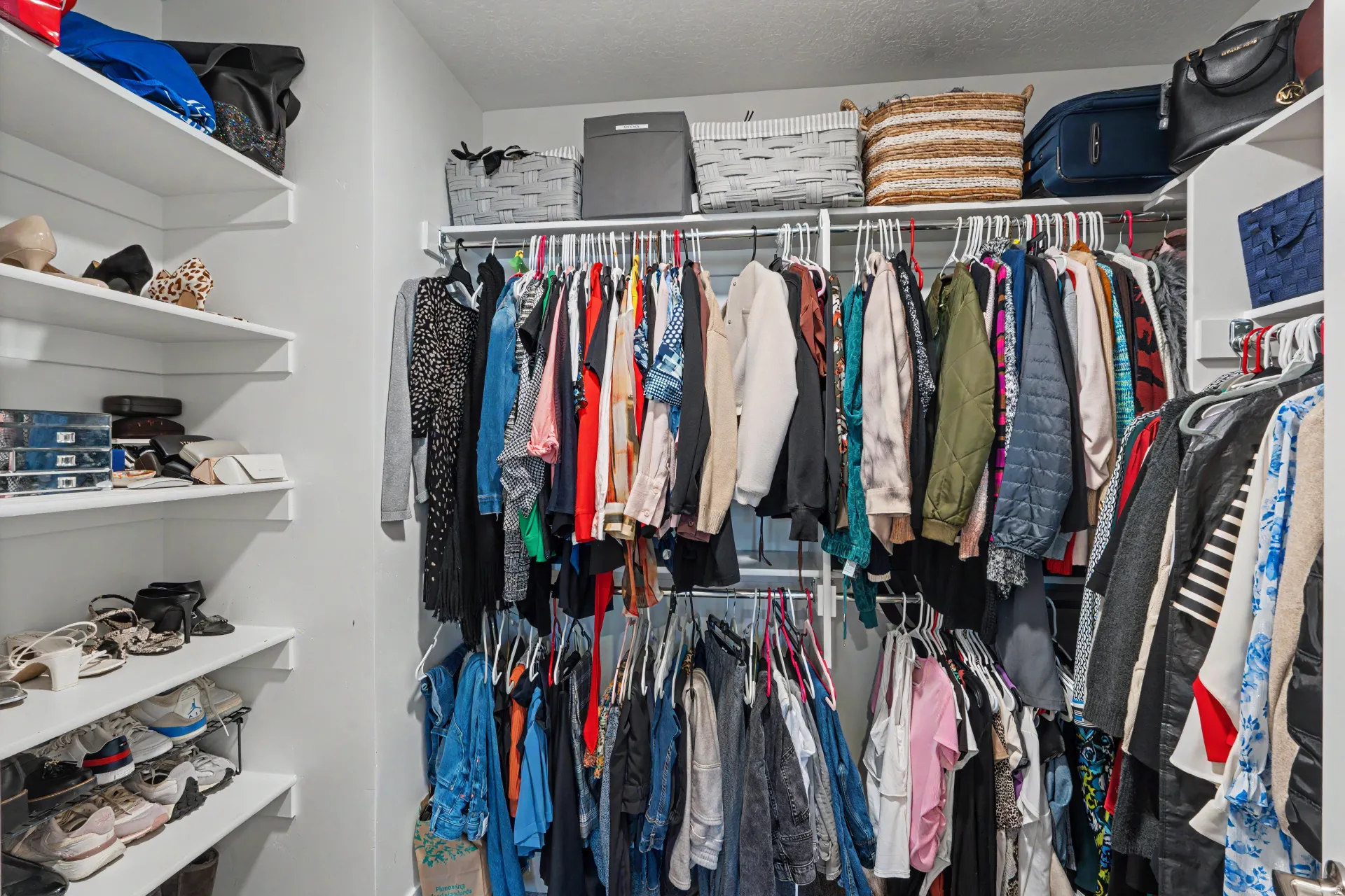 Custom closet system with white shelving and multiple hanging rods