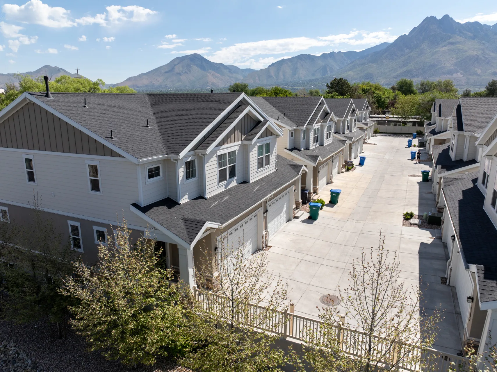 Townhome exterior featuring light-toned siding with dark shingle roofing and white trim accents