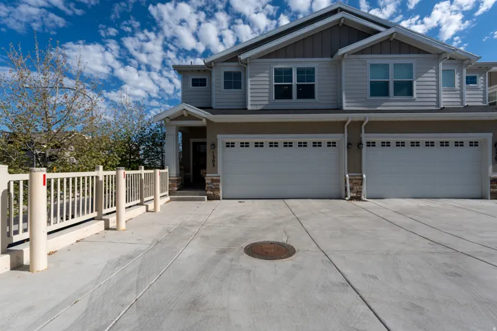 Multi-story property featuring light gray horizontal siding and a two-car garage with white paneled doors