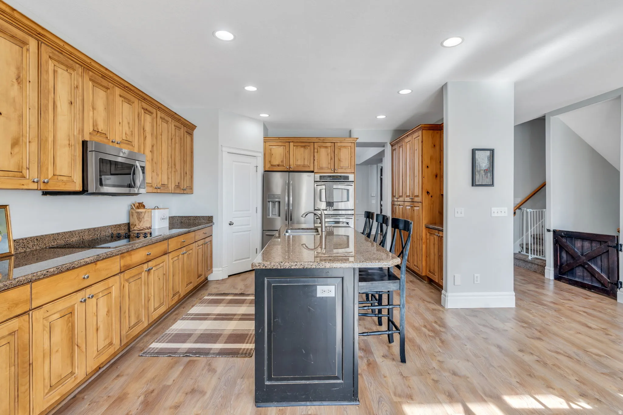 Kitchen featuring a kitchen bar, dual tone cabinets, stainless steel appliances, a kitchen island with sink