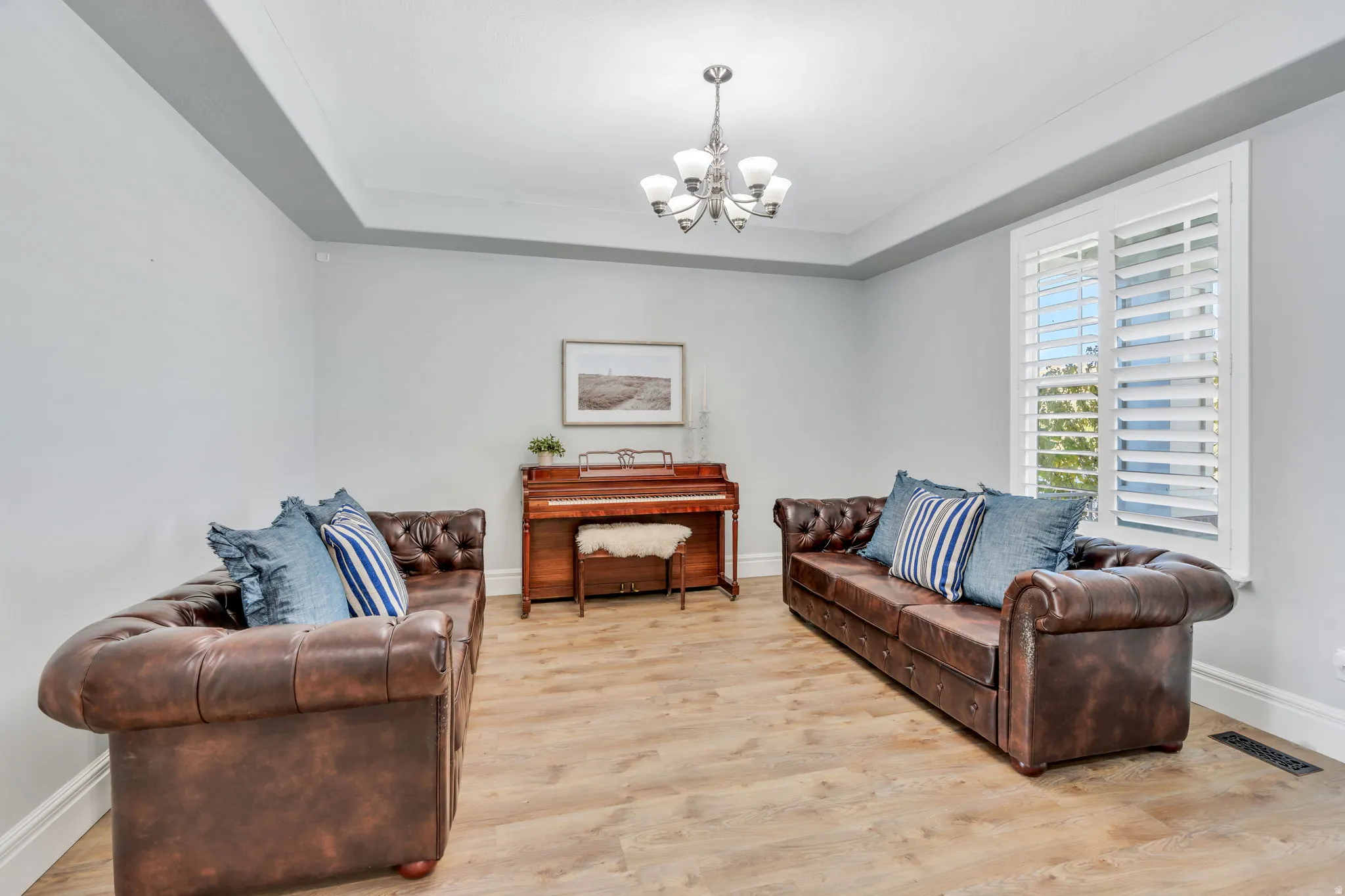Formal living room with light LVP floors, and a raised ceiling