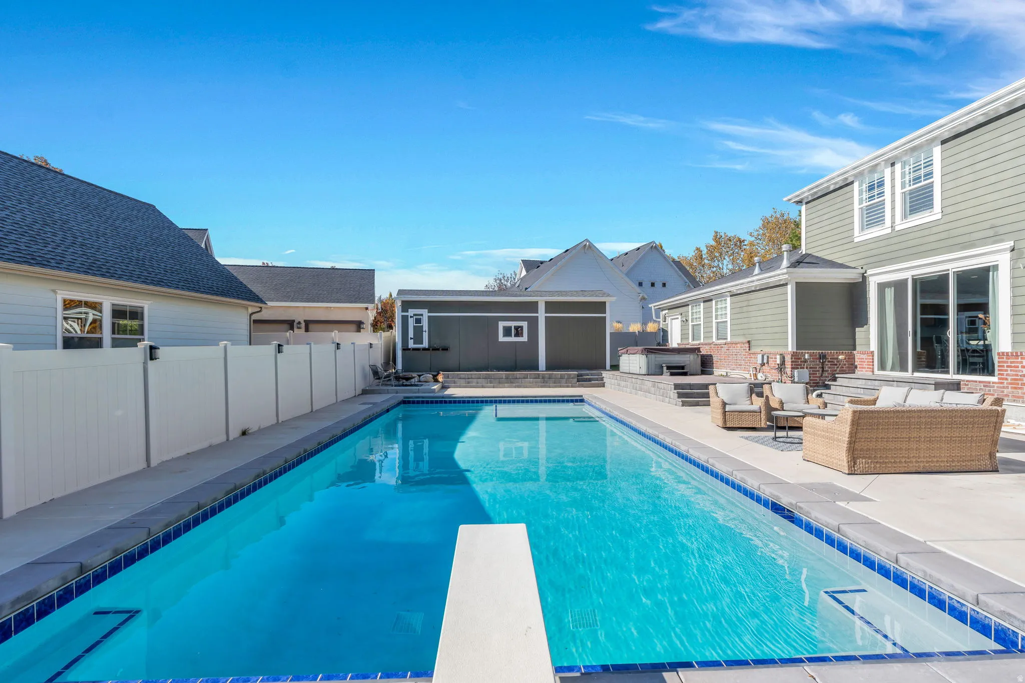 View of pool with diving board, featuring patio surround, a fenced backyard, and an outdoor lounge area