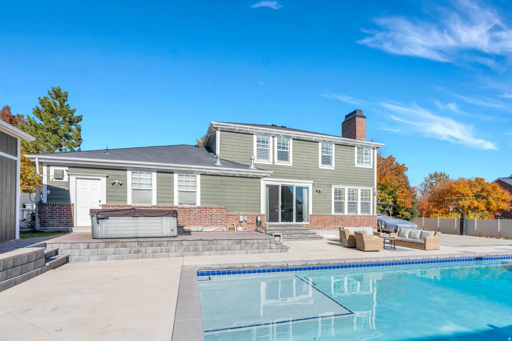 Back of house featuring entry steps, a patio area, and hot tub
