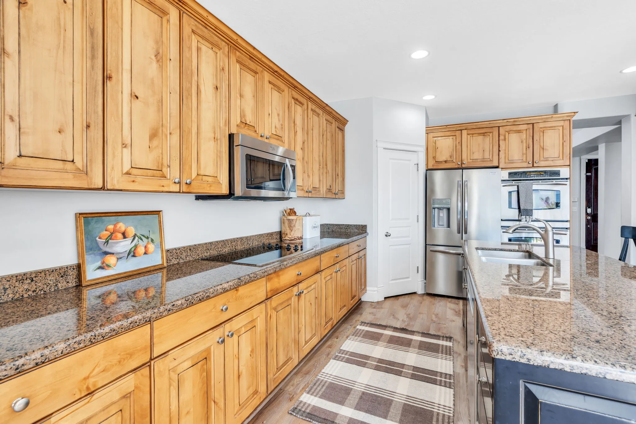 Kitchen featuring stainless steel appliances, granite countertops, recessed lighting, and an island with sink