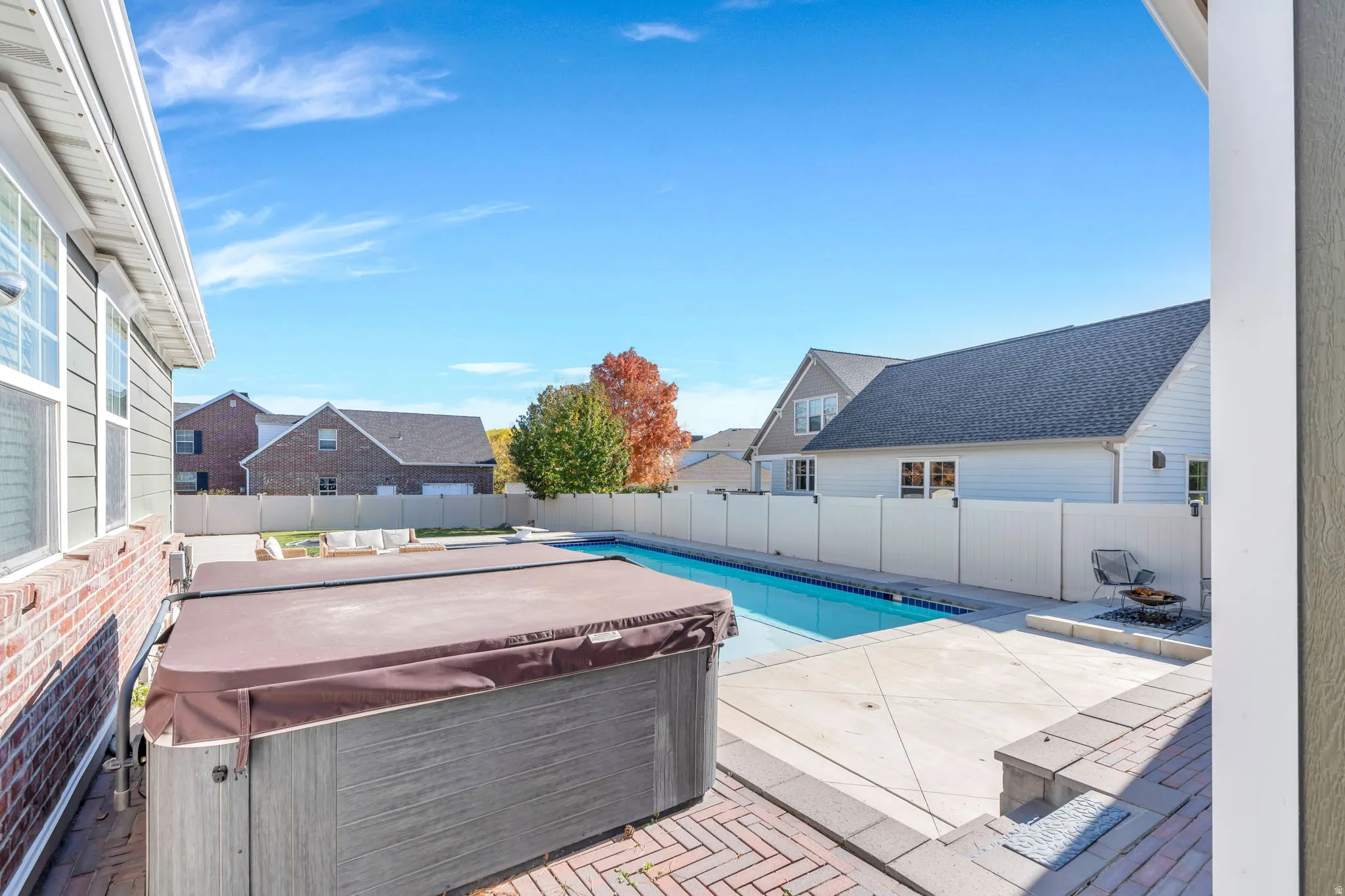 View of jacuzzi and pool in a fully fenced yard