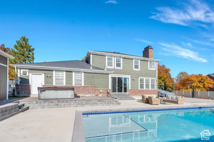 Back of house featuring entry steps, a patio area, and hot tub